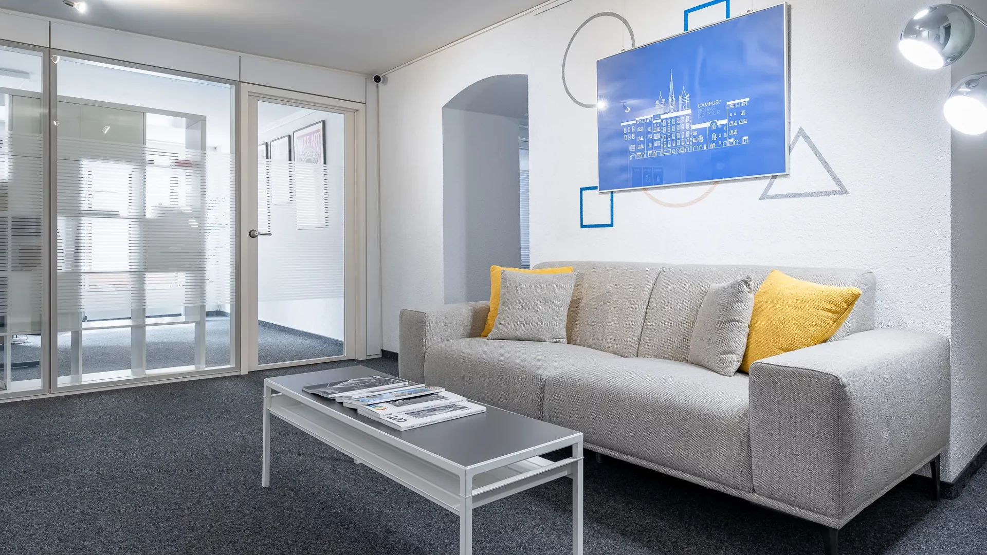 espace lounge commun avec canapé et tableau